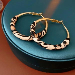 Gros plan de créoles dorées enveloppées de tissu léopard sur un coffret à bijoux bleu