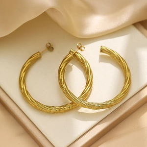 Golden twisted rope mesh hoop earrings in stainless steel on elegant silk background