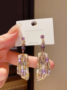 Close-up of S925 silver needle earrings with purple crystal pendants and gold plating