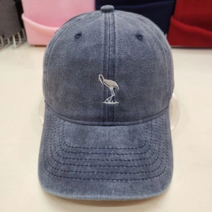 Washed denim baseball cap in dark blue featuring a white bird embroidery on the front