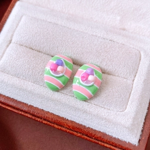 Macro shot of striped oval earrings with colorful beads in a velvet jewelry box