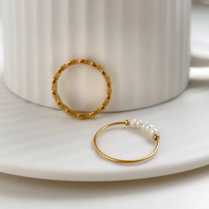 Detail of gold geometric textured ring and white pearl band on elegant ceramic tray