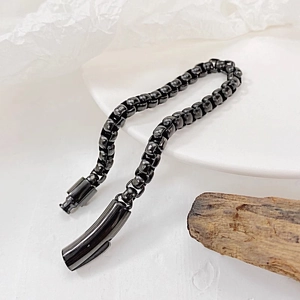 Macro detail of gunmetal black square box chain bracelet with a cylindrical clasp