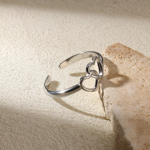Close-up of interlocking heart-shaped cutouts on a polished silver adjustable open ring