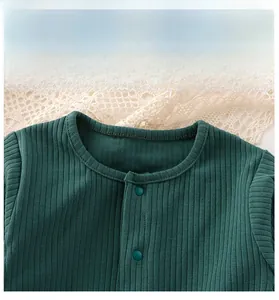 Dettaglio dello scollo della tutina per neonati con bottoni a pressione in cotone verde