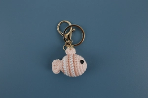 Detailed view of handmade crochet pink and white clownfish keychain with golden metal ring