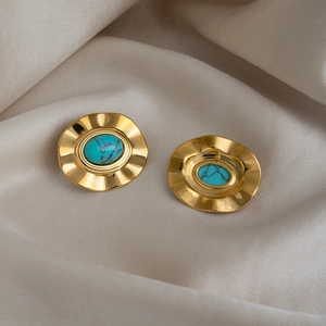 Makroaufnahme goldener Vintage-Ohrringe mit Türkisstein auf Seidenstoff