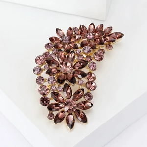 Detailed close-up of floral brooch with purple crystals on a golden base