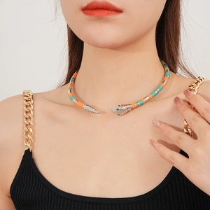 Detail of snake-shaped choker with orange and turquoise beads on female neck