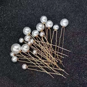 Macro detail of bridal hair pins set with assorted sizes of white faux pearls and gold U-shaped clips
