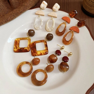 Close-up of resin and wood geometric drop earrings in amber and tortoiseshell patterns