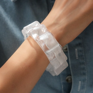 Dettaglio di un bracciale in resina bianca traslucida con bordi a onde sulla pelle