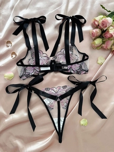 Detail of sheer mesh lingerie set featuring pink butterfly embroidery and black satin bows