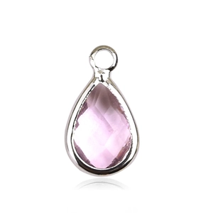 Macro shot of a teardrop-shaped pink crystal pendant with a polished silver-tone border