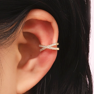 Close-up of golden X-shaped ear cuff featuring pavé-set crystals on a female model