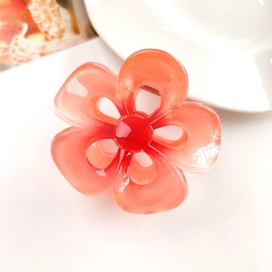 Macro detail of a coral pink gradient plumeria hair claw clip with a resin flower design