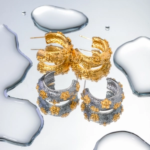 Detailed macro view of 18k gold C-shaped earrings with hammered texture and floral design