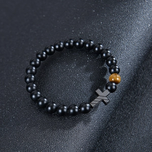 Detailed shot of matte black beads and brown tiger eye stone on a leather texture surface