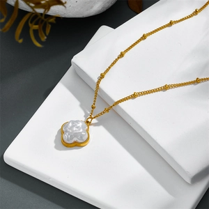 Elegant gold-plated stainless steel necklace with pearl clover pendant on a stone base