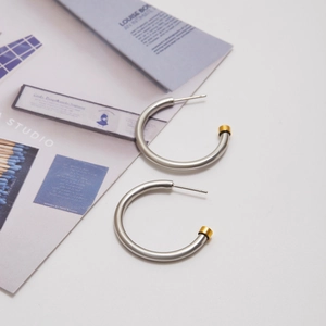 Detailed close-up of C-shaped silver and gold hoop earrings on minimalist magazine background