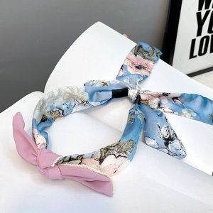 Detail of blue floral fabric headband with a pink bow accent in a Korean style design