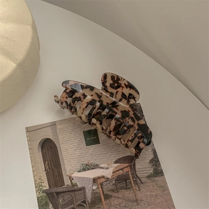 Detail of tortoise shell acetate hair claw clip showing glossy texture and curved teeth