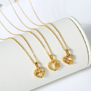 Three gold stainless steel heart necklaces with zircons on a white jewelry stand