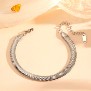Detail view of silver snake bone chain bracelet with lobster clasp on soft peach fabric