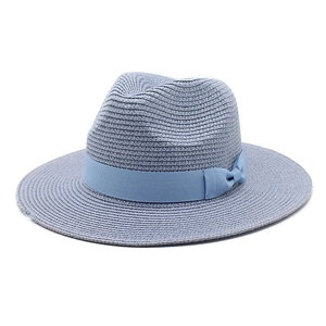 Detail of blue straw sun hat with decorative grosgrain ribbon bow on a white background