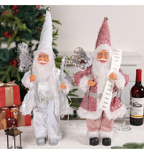 Standing Santa Claus dolls in pink and silver sequins by a cozy fireplace and tree