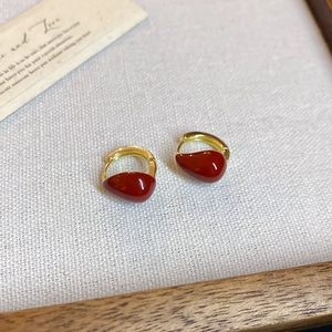 Detail view of retro gold earrings with red drop pendant on rustic linen background