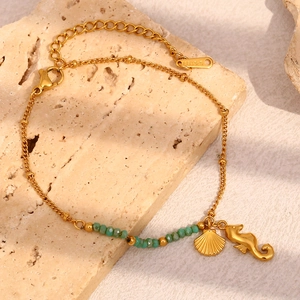 Gros plan de pendentifs hippocampe dorés et perles turquoise sur fond rocheux