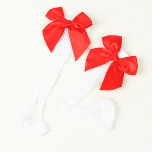 Detail view of white fishnet mesh socks featuring a vibrant red satin ribbon bow accent