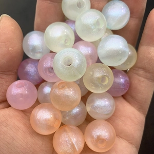 Luminous pearlescent round beads for DIY jewelry making held in palm to show size