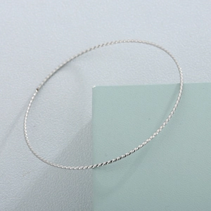 65mm twisted rope bangle in silver-tone stainless steel on minimalist blue display