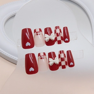 Short ballet nails with red checkerboard heart patterns and 3D bow accessories