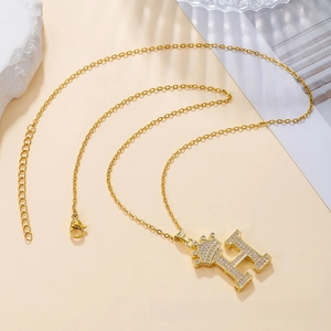 Macro shot of gold H-letter crown pendant necklace with pavé cubic zirconia details