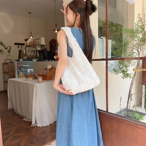 Sac fourre-tout d'été en dentelle sur mannequin avec robe en jean dans un café confortable