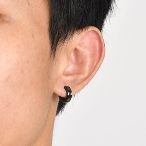 Close-up of black stainless steel hoop earring with three stripes on a male ear