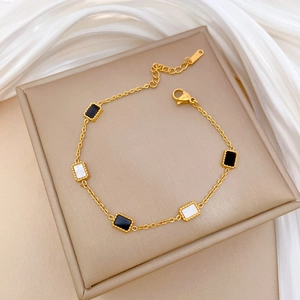 Gold titanium steel bracelet featuring black and white rectangular charms on leather display
