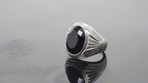 Macro view of men's silver ring featuring a large oval black gemstone and textured band