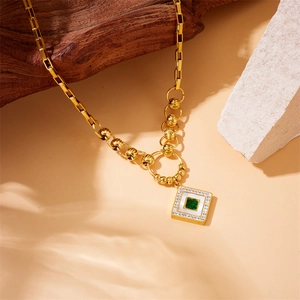 Detail of gold-plated multi-layer chain with square green gemstone and white inlay