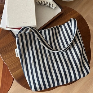 Close-up of navy and white striped canvas tote bag texture with simple wish label on wood