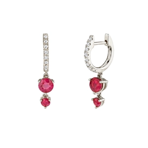 Macro detail of silver hoop earrings with micro-set zircons and red gemstone drops