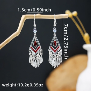 Detail shot of bohemian tassel earrings with red gemstones hanging on a branch