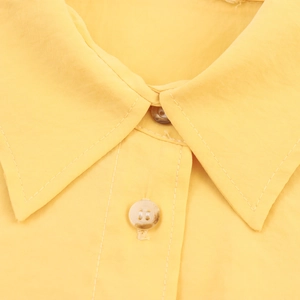 Women's bright yellow collared long sleeve shirt with marble texture buttons and stitching