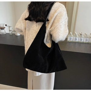 Detail of a large black suede hobo bag with a wide shoulder strap for chic daily commuting