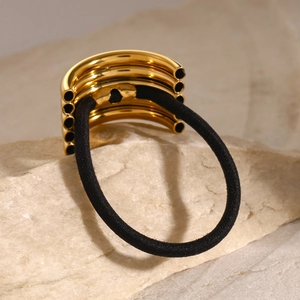 Polished gold multi-layer metal hair tie with durable black elastic band on stone background