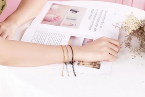 Three minimalist stainless steel snake bracelets in gold, silver, and black on a wrist
