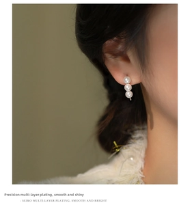 Detail of s925 silver hook earrings with three vertical white pearls on model